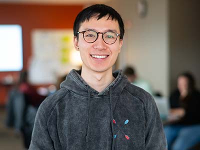 Asian man late 20s early 30s with glasses smiling at camera