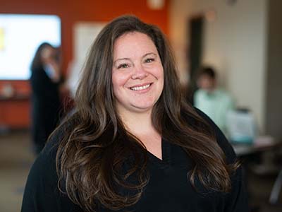 Friendly smiling woman with long brown hair and a dark button front shirt