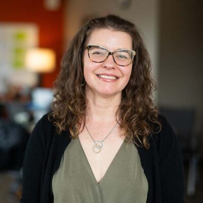 TAP assistant director Mary Beth McNulty wearing her long curly hair down, glasses and a big smile